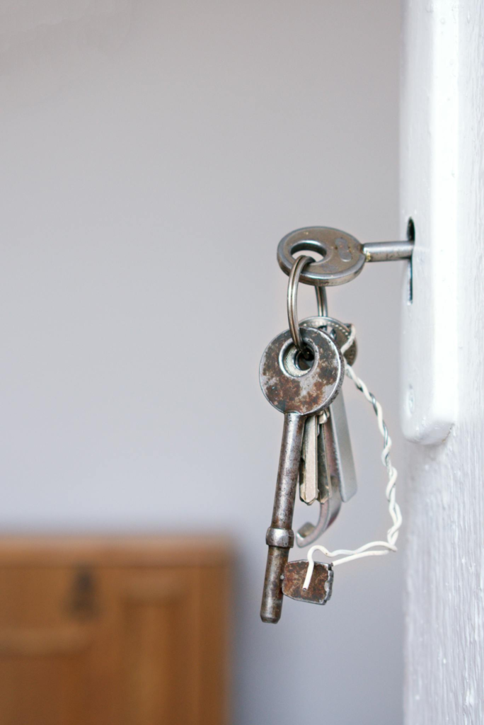 Close-up of vintage keys in a door keyhole with rustic metal and wood textures.